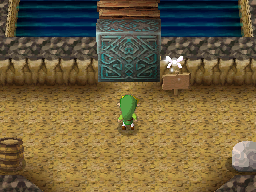 A screenshot of Link standing in the first part of the Storehouse. A stone Door blocks his way while Ciela hovers over a nearby Sign.