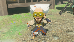 A screenshot of Robbie appearing shocked inside Lookout Landing. Text on-screen displays his name, along with the title "Head of Purah Pad Development".
